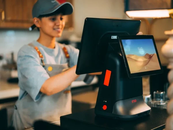 A cashier using a modern point of sale terminal in a store.