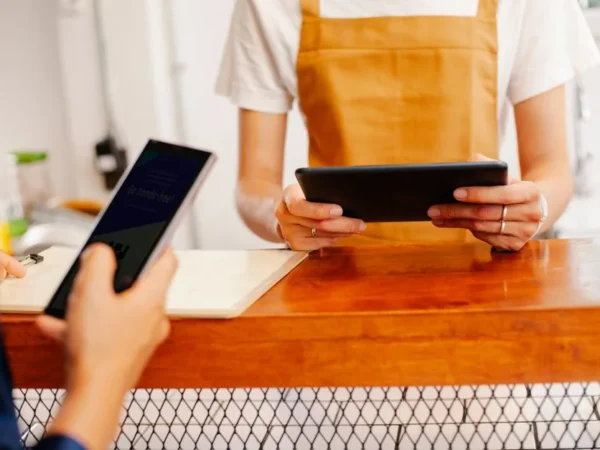 Crop anonymous female colleagues surfing internet on cellphone with black screen and tablet in cafe