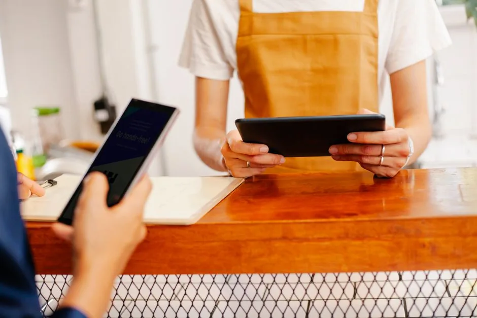 Crop anonymous female colleagues surfing internet on cellphone with black screen and tablet in cafe