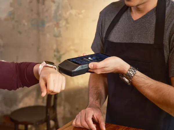Smartwatch user making a contactless payment at a café using a POS device.