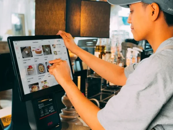 A cafe worker navigating a modern touchscreen system to manage orders efficiently.